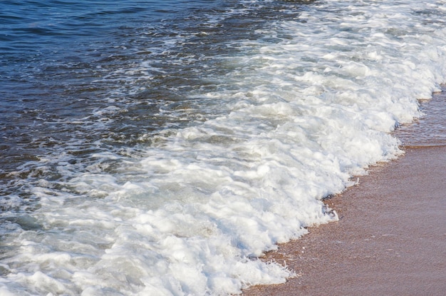 Douce vague de mer sur fond de plage de sable