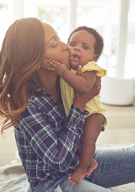 La doucher de baisers Photo recadrée d'une jeune mère et de sa petite fille à la maison