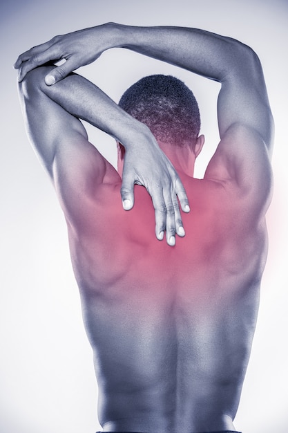 Photo douleur articulaire. vue arrière du jeune homme africain musclé touchant son cou et son coude en se tenant debout sur fond gris