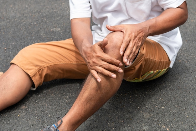 Douleur asiatique jambe senior homme pendant le jogging dans le parc.