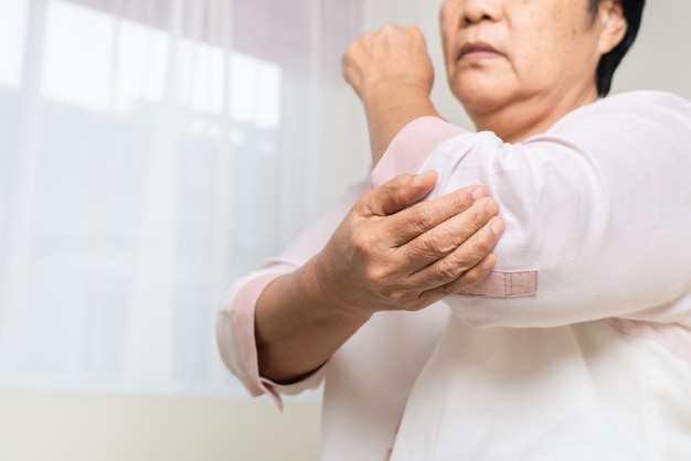 Douleur au coude vieille femme souffrant de douleurs au coude à la maison, problème de santé du concept senior