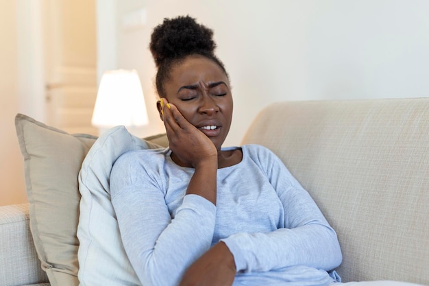 Douleur dentaire et dentisterie Belle jeune femme souffrant de terribles dents fortes Douleur touchant la joue avec la main Femme se sentant douloureuse Mal de dents Concept de soins dentaires et de santé Haute résolution