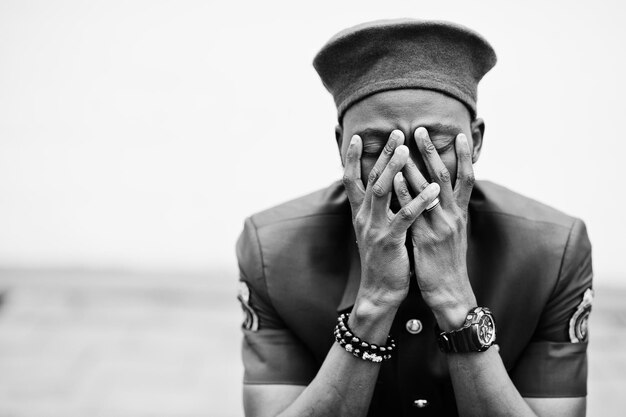 Douleur de guerre. Portrait d'un militaire afro-américain en uniforme rouge et béret couvre son visage avec ses mains.