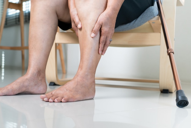 Douleur à la jambe d'une femme âgée à la maison, problème de santé du concept senior