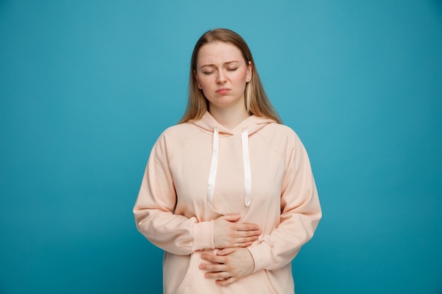 Douleur jeune femme blonde en gardant les mains sur le ventre avec les yeux fermés