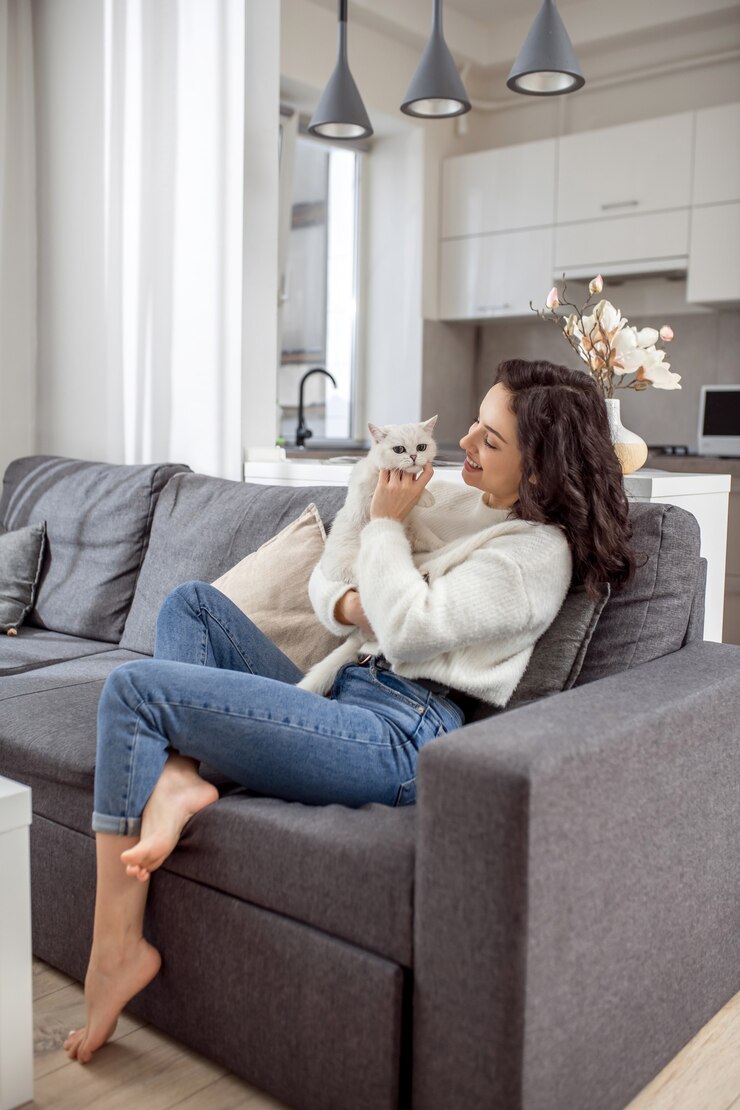 Photo doux ami. jeune femme en pull blanc et son chat à la maison