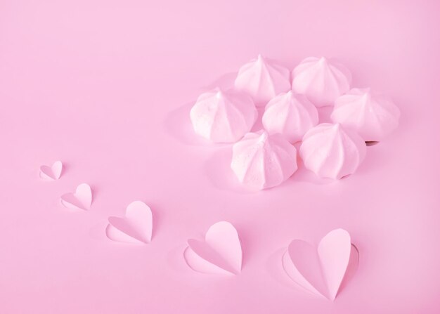 Doux baiser de meringue Dessert fond monochrome rose avec des coeurs le jour de la Saint-Valentin