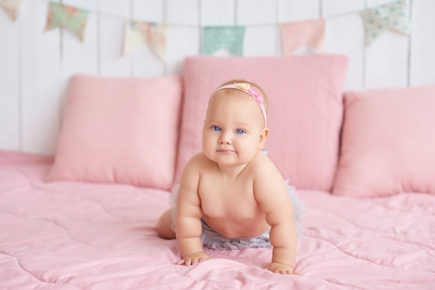 Doux bébé drôle sur le lit dans la chambre des enfants.Mignon bébé fille 6 mois assis et rampant.