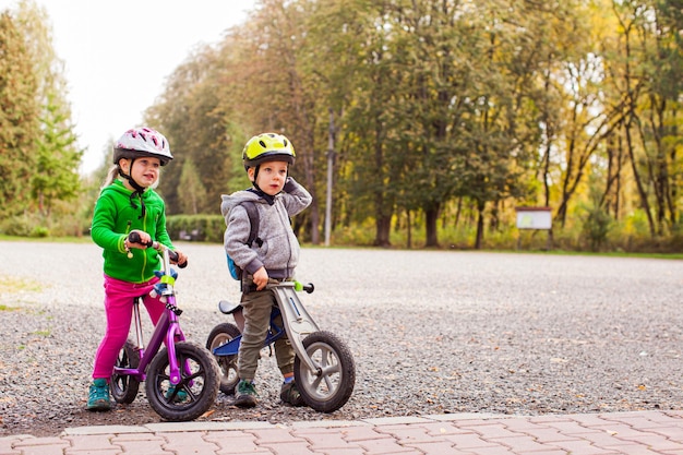 Doux enfants sur des vélos d'équilibre à l'extérieur au parc