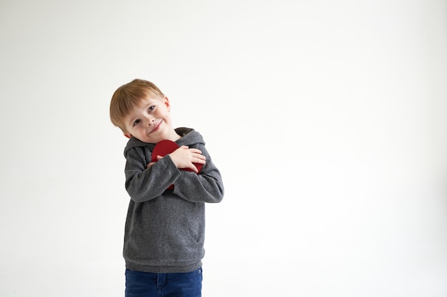 Doux garçon tenant coeur de papier rouge sur fond blanc concept médical de soins de santé pour enfants