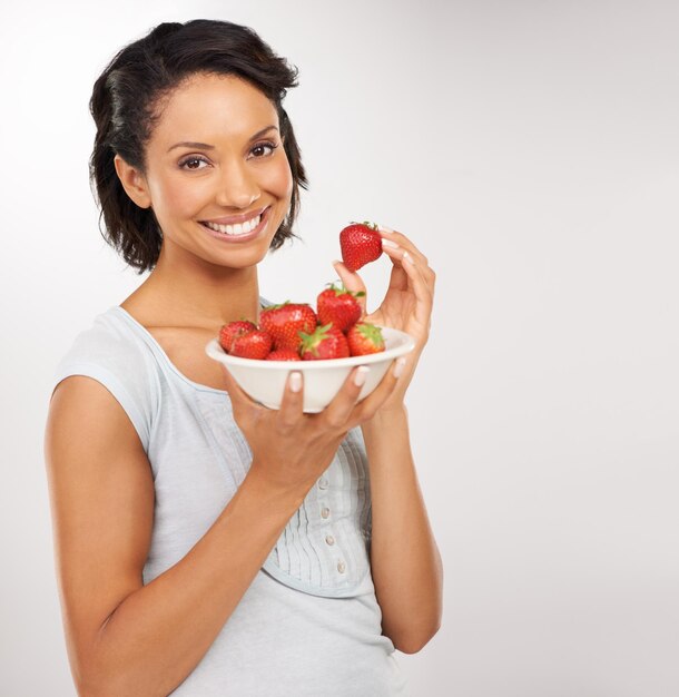 Doux juteux et absolument délicieux Portrait d'une jeune femme dégustant un bol de fraises