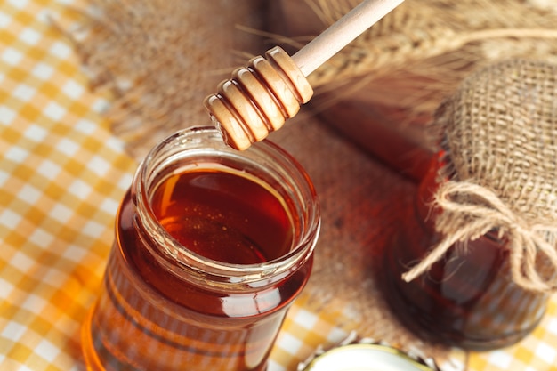 Doux miel en pot de verre sur fond en bois.