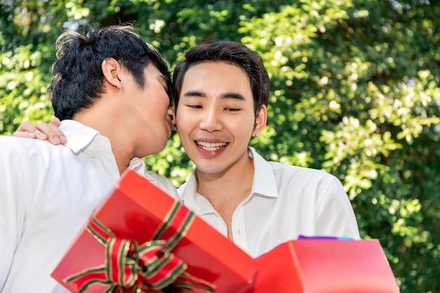 Doux moment d'amour Portrait d'un couple homosexuel asiatique câlin et cadeau de boîte surprise à un petit ami