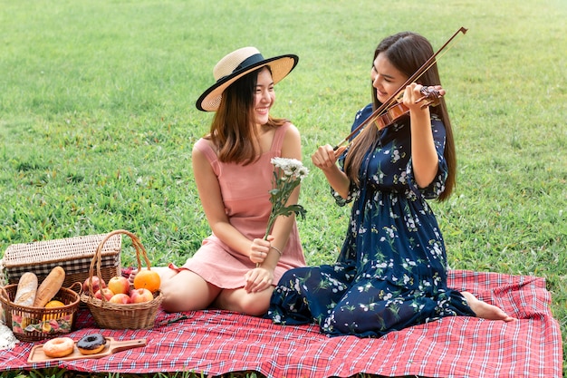 Doux moment d'amour.Portrait de couple homosexuel asiatique jouant avec le violon et pique-nique dans le parc.Concept LGBT leasbian.