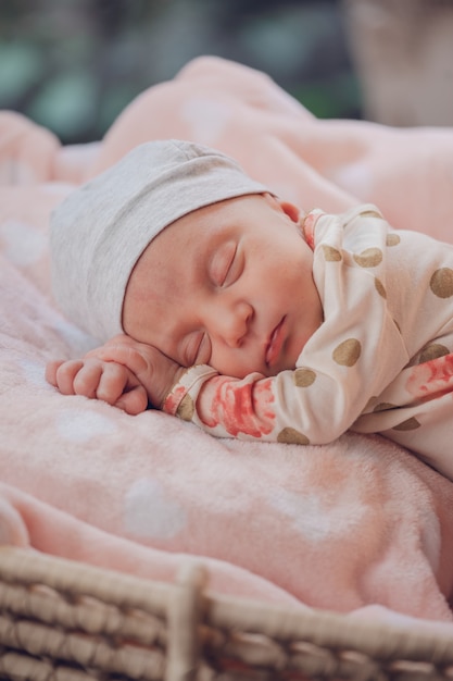 Photo doux petit bébé dormant dans un panier sur une couverture rose