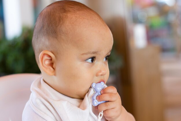 Doux petit bébé garçon assis dans une chaise haute au restaurant et jouet à mâcher