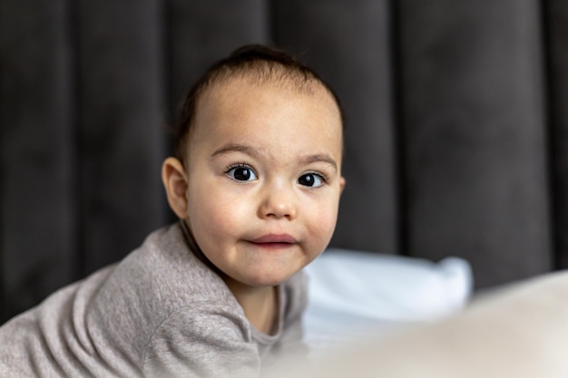 Doux petit garçon sur le lit tout-petit juste éveillé drôle de visage d'enfant joufflu