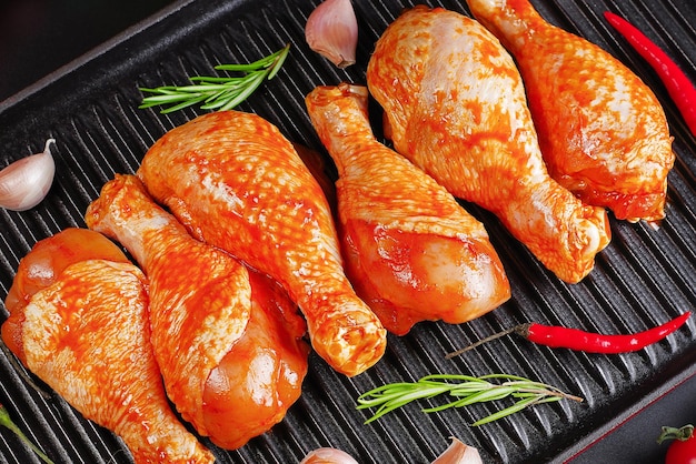 Dramsticks de poulet marinés au barbecue sur une planche de cuisson noire sur fond noir avec du romarin frais