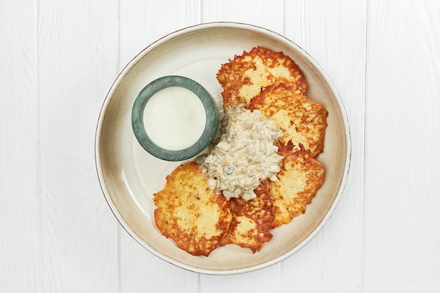 Draniki ukrainien de pommes de terre ou pommes de terre rissolées dans une assiette sur un fond de bois blanc