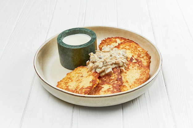 Draniki ukrainien de pommes de terre ou pommes de terre rissolées dans une assiette sur un fond de bois blanc