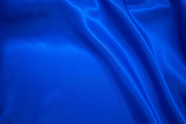 Drapé textile en tissu soyeux en satin bleu abstrait avec fond de plis ondulés de pli