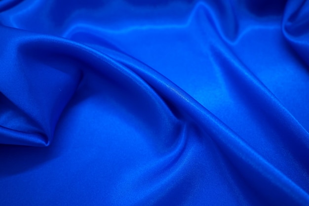 Drapé textile en tissu soyeux en satin bleu abstrait avec fond de plis ondulés de pli