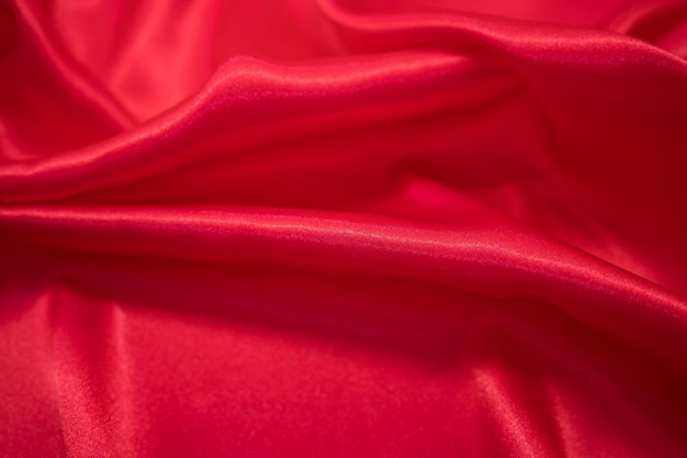 Drapé textile en tissu soyeux en satin rouge abstrait avec fond de plis ondulés de pli