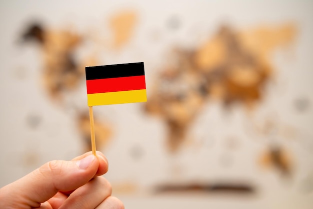 Drapeau de l'Allemagne dans la main de l'homme sur la carte du monde en bois fond économie mondiale et concept géopolitique