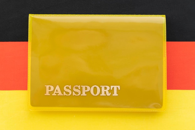 Drapeau de l'Allemagne avec passeport Visa de voyage et concept de citoyenneté permis de séjour dans le pays un document jaune avec l'inscription passeport est sur le drapeau Vue rapprochée du dessus