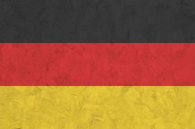 Drapeau de l'Allemagne représenté dans des couleurs vives de peinture sur le vieux mur de plâtrage en relief. Bannière texturée sur fond rugueux
