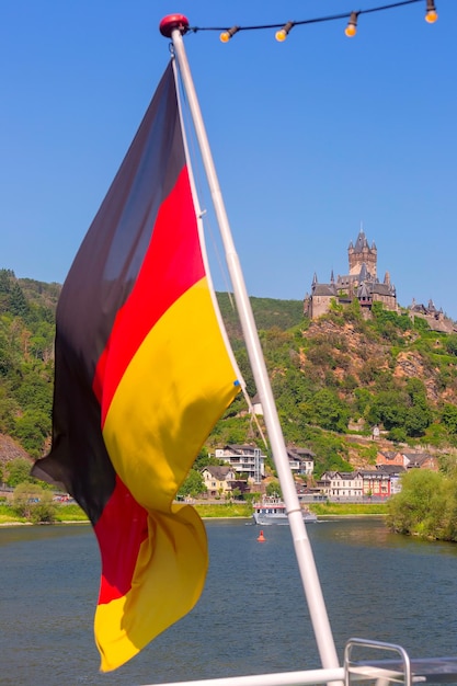 Le drapeau allemand flotte sur le fond du château de Reichsburg à Cochem, en Allemagne.