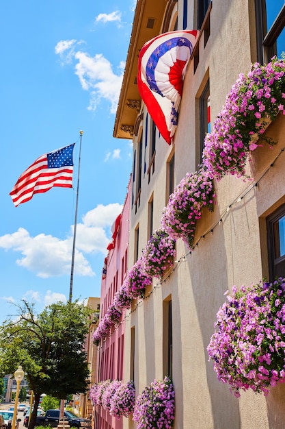 Drapeau américain et couleurs par mur recouvert de fleurs de jardinière rose