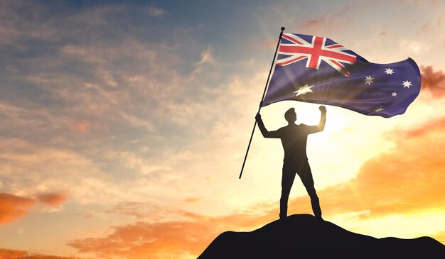Drapeau de l'Australie agité par un homme célébrant le succès au sommet d'une montagne Rendu 3D