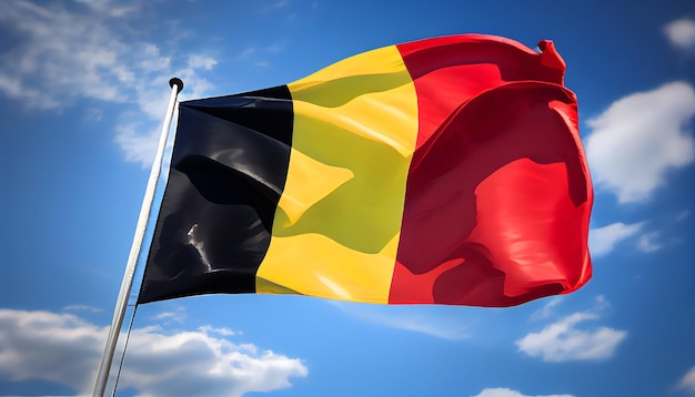 Le drapeau belge agitant fièrement dans le vent entouré d'un ciel bleu clair et de nuages blancs moelleux évoquant un sentiment de fierté et d'unité nationales