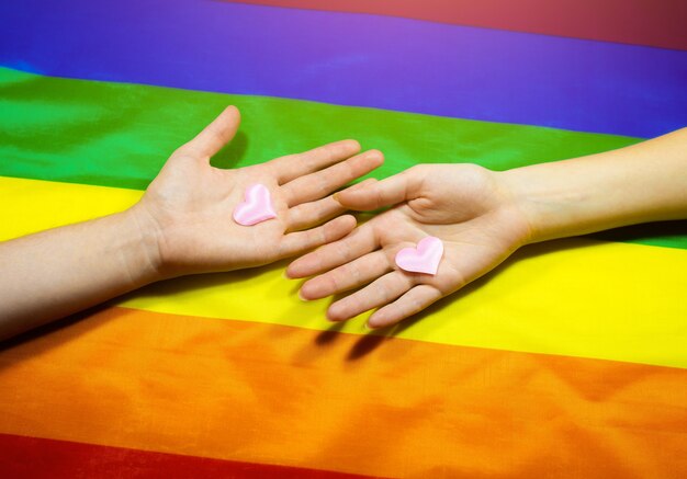 Drapeau coloré de la communauté LGBT. Deux mains de femmes sur fond arc-en-ciel. Problèmes lesbiens et gays. Légalisation du mariage pour les couples homosexuels.