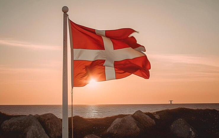 Photo un drapeau danois sur un poteau avec le soleil derrière lui