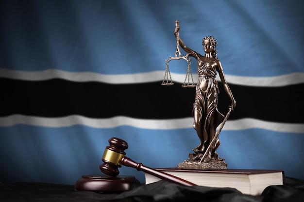 Drapeau du botswana avec statue de dame justice constitution et juge marteau sur draperie noire Concept de jugement et de culpabilité