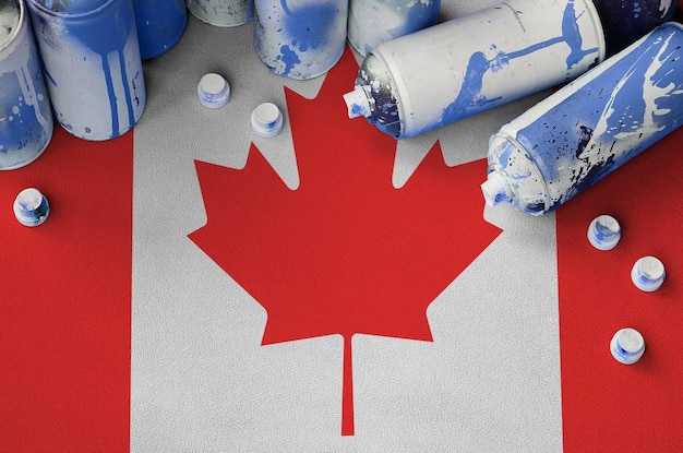 Photo drapeau du canada et quelques aérosols utilisés pour la peinture de graffitis concept de culture d'art de rue