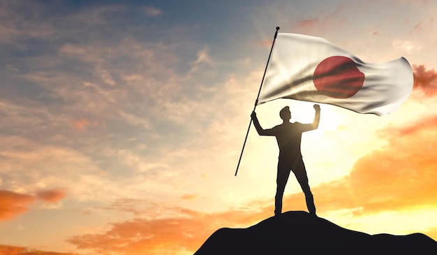 Drapeau du Japon agité par un homme célébrant le succès au sommet d'une montagne Rendu 3D