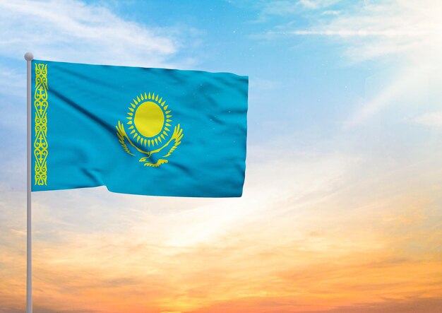 Le drapeau du Kazakhstan étendu sur un mât de drapeau et en arrière-plan un beau ciel avec un coucher de soleil