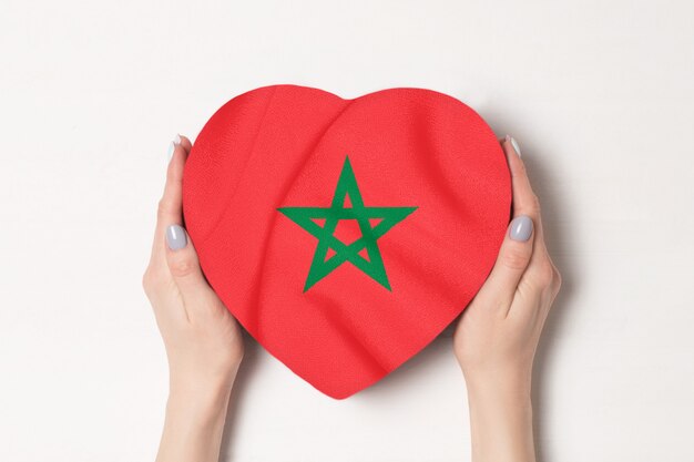 Drapeau du Maroc sur une boîte en forme de coeur dans une main féminine