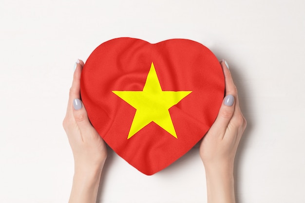 Drapeau du Vietnam sur une boîte en forme de coeur dans une main féminine