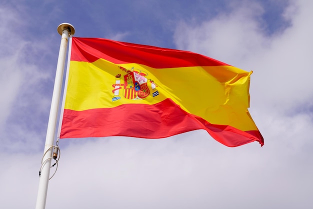 Le drapeau espagnol de l'Espagne flotte au-dessus du ciel dans le tapis avec le vent