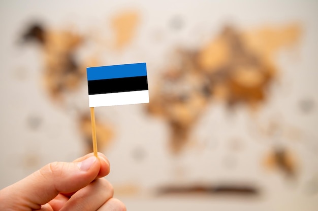 Drapeau de l'estonie dans la main de l'homme sur la carte du monde en bois fond économie mondiale et concept géopolitique