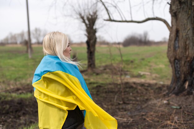 Drapeau de la femme de l'ukraine près de l'arbre brûlé