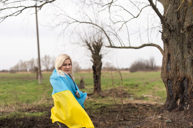 drapeau de femme de l'ukraine près de l'arbre brûlé.