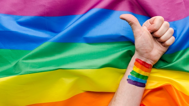 Photo drapeau de fierté arc-en-ciel et pouce en l'air