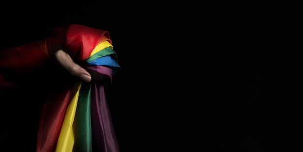 Drapeau de fierté. Drapeau et main LGBTQ. Lesbiennes Gay Bi sexsual Transgenre Queer ou fierté homosexuelle Drapeau arc-en-ciel. fond noir.