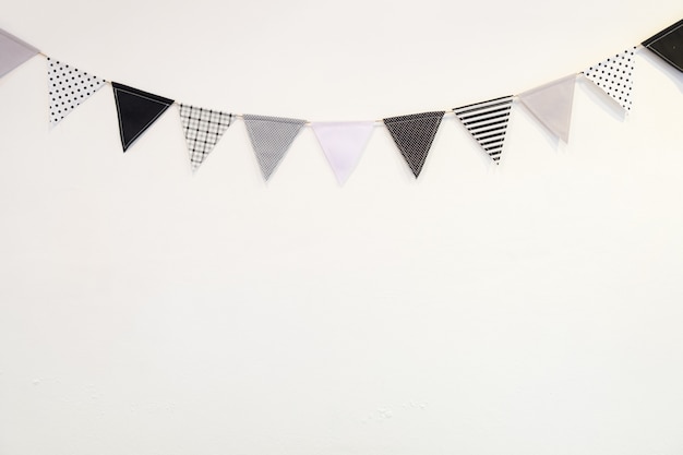 Photo drapeau de forme de petit triangle blanc noir suspendu courbe vers le bas du mur de plâtre