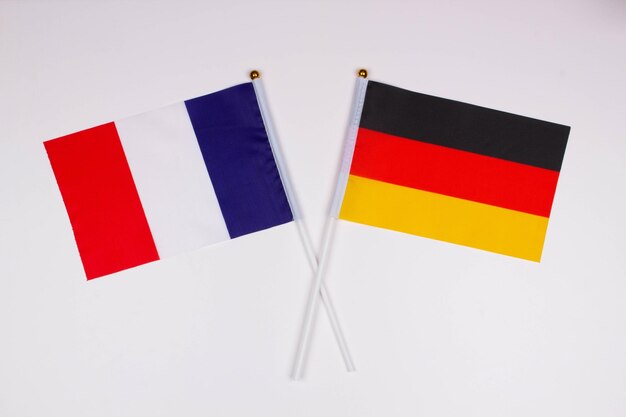 Photo drapeau de la france et drapeau de l'allemagne croisés sur un fond blanc isolé